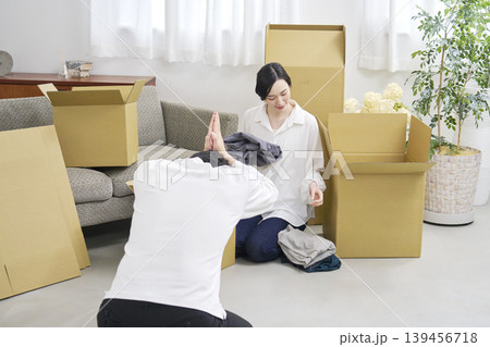 引越し中に土下座で謝る男性と荷物を整理する女性 139456718
