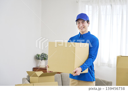 段ボールを持つ笑顔の引っ越し業者の男性 139456738
