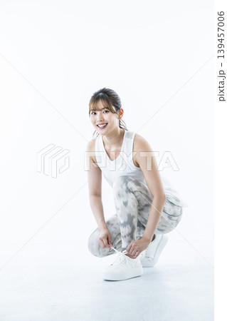 靴紐を結ぶスポーツウェアを着た若い女性 139457006