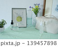 Skincare products and cosmetic bag with decorative flowers and frame on a mint green cloth. 139457898