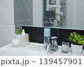 Aesthetic bathroom sink counter with skincare bottles, potted succulents, and clean tiles. 139457901