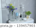 Minimalist bathroom decor with assorted toiletries and floral arrangement against a tiled wall. 139457903