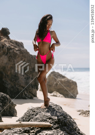 Woman in pink swimwear posing on beach, enjoying summer vibes 139458032