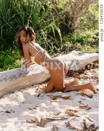 Asian woman in bikini at tropical sunny beach. Lady with slim body posing at ocean coastline Asian woman in bikini at tropical sunny beach. Lady with slim body posing at ocean coastline 139458039