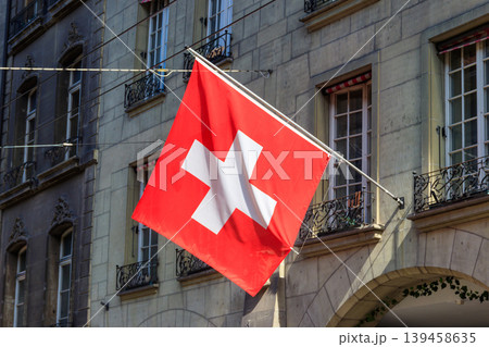 Red Swiss flag hanging from building facade 139458635