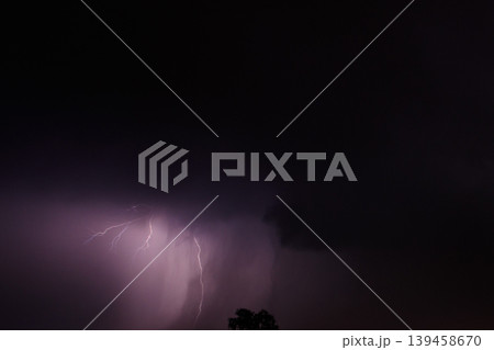 Lightning discharges in the stormy sky under dark rain clouds at night Lightning discharges in the stormy sky under dark rain clouds at night 139458670