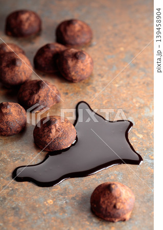 Chocolate truffles and chocolate sauce against a rusty background. Chocolate truffles and chocolate sauce against a rusty background. 139458904
