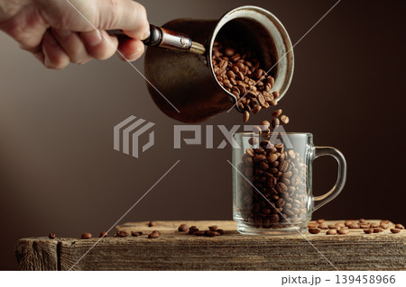 Roasted coffee beans is poured in a clear glass mug. 139458966