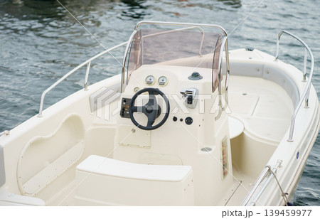 Close view of motorboat cockpit with steering wheel and instruments, leisure boating, navigation concept and calm water background Close view of motorboat cockpit with steering wheel and instruments, leisure boating, navigation concept and calm water background 139459977