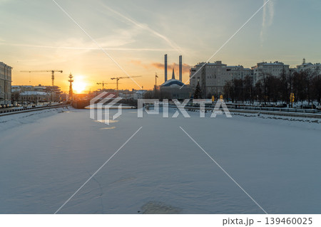 Winter City River Sunset With Snow-Covered Embankment And Urban Skyline Winter City River Sunset With Snow-Covered Embankment And Urban Skyline 139460025