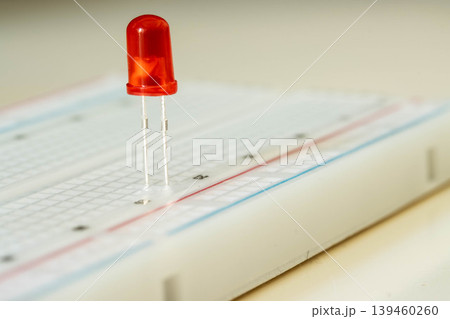 Red LED on breadboard close up, electronic component concept 139460260