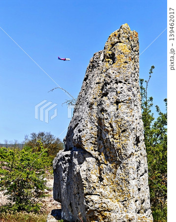 a plane appearing to land on a giant natural stone column. 139462017