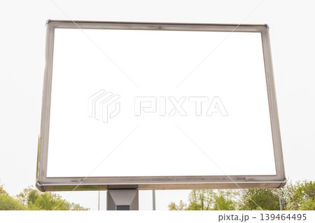 A blank billboard is positioned in a public space surrounded by trees. The sky is cloudy, and the scene shows no advertisements or messages. It appears to be a quiet day A blank billboard is positioned in a public space surrounded by trees. The sky is cloudy, and the scene shows no advertisements or messages. It appears to be a quiet day 139464495