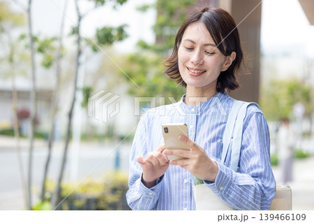 屋外でスマホを操作するミドル女性 139466109