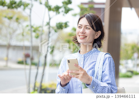 屋外でスマホを操作するミドル女性 139466111
