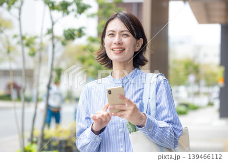 屋外でスマホを操作するミドル女性 屋外でスマホを操作するミドル女性 139466112