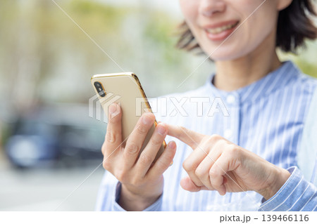 屋外でスマホを操作するミドル女性 屋外でスマホを操作するミドル女性 139466116