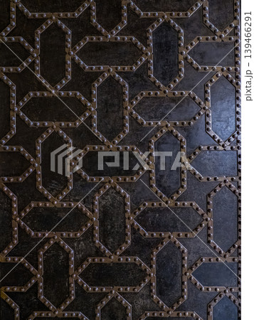 Antique Riveted Iron Door Panel With Geometric Pattern and Dark Textured Metal Surface 139466291