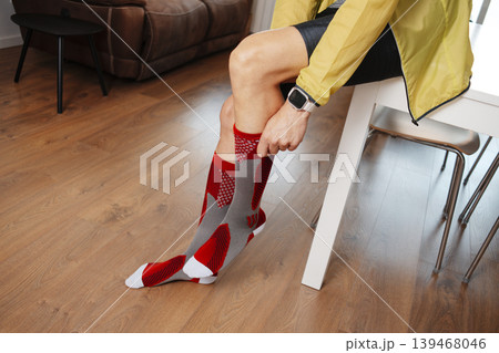 a man fits a compression sock before going running a man fits a compression sock before going running 139468046