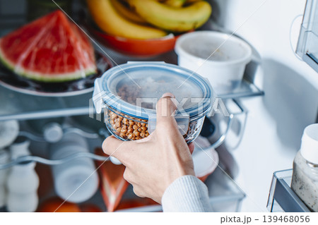 a man places a container of lentils in the fridge a man places a container of lentils in the fridge 139468056