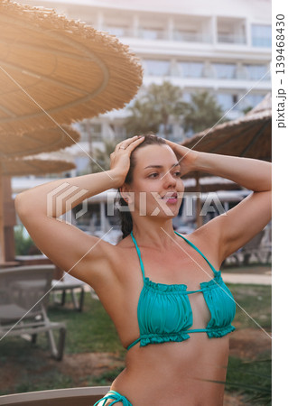 Beautiful woman touching hair with glowing radiant healthy bronzed summer skin outdoors gracefully. Beautiful female showing smooth fresh body texture during tropical resort vacation beside luxury Beautiful woman touching hair with glowing radiant healthy bronzed summer skin outdoors gracefully. Beautiful female showing smooth fresh body texture during tropical resort vacation beside luxury 139468430