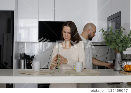 Beautiful woman and man enjoying a cup of drink in the morning together at home in their kitchen.  139469047