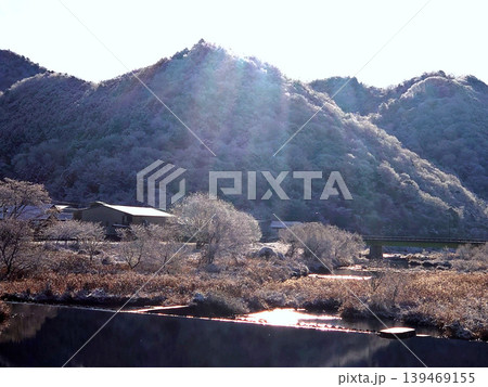 朝日に輝く雪化粧の山並みと冬の静かな里山風景 139469155