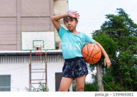 Asian student girl holding a basketball and standing on the school basketball court, Back to school and healthy lifestyle concept. Asian student girl holding a basketball and standing on the school basketball court, Back to school and healthy lifestyle concept. 139469361