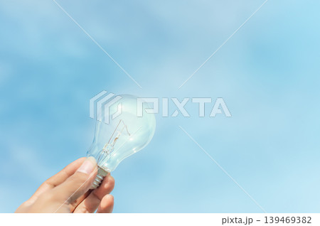 Clear Light Bulb with Blue Sky Background, Concept of Clean Energy and Sustainable Future 139469382