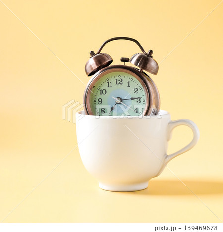Vintage Alarm clock in white coffee cup. Vintage Alarm clock in white coffee cup. 139469678