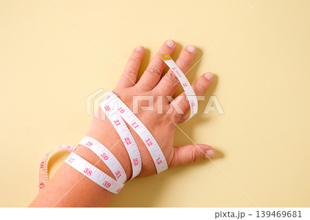 A measuring tape is wrapped around hand. 139469681