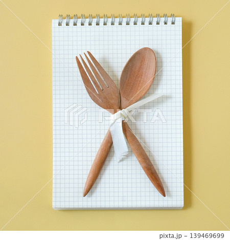 Wood fork and spoon on booknote on color background. Wood fork and spoon on booknote on color background. 139469699