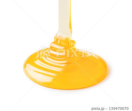 Golden honey pouring creating sweet liquid puddle Golden honey pouring creating sweet liquid puddle 139470070