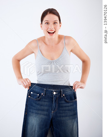 Woman, lose weight and portrait of surprise with jeans, change in size or white background in studio. Wow, shocked and person with crazy transformation in fitness, health or comparison in denim pants Woman, lose weight and portrait of surprise with jeans, change in size or white background in studio. Wow, shocked and person with crazy transformation in fitness, health or comparison in denim pants 139470126