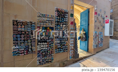 Souvenirs such as  magnets and postcards on the wall in touristic street in Gozo 139470156