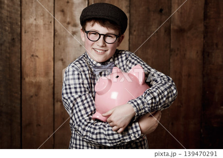 Young child, hugging and piggy bank in portrait in studio background, retro money safe and cash savings in youth. Boy, smile and face for coin banking in vintage fashion and happy for dollars profit Young child, hugging and piggy bank in portrait in studio background, retro money safe and cash savings in youth. Boy, smile and face for coin banking in vintage fashion and happy for dollars profit 139470291