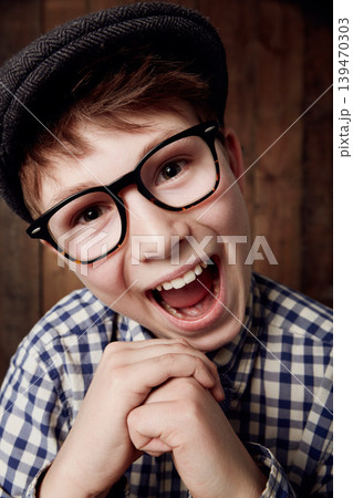 Glasses, portrait and happy for boy in funny comic and vintage fashion in eyewear by wooden background. Child, face or laughter for comedy or retro clothes, spectacles or joke for smart for vision Glasses, portrait and happy for boy in funny comic and vintage fashion in eyewear by wooden background. Child, face or laughter for comedy or retro clothes, spectacles or joke for smart for vision 139470303