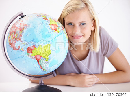 Portrait, smile and globe for travel with a woman in studio on a white background for holiday destination. Face, earth or planet with a happy young person looking at a location for world vacation 139470362
