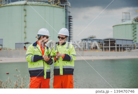Two safety engineers in field gear coordinating operations with walkie and tablet at plant 139470746