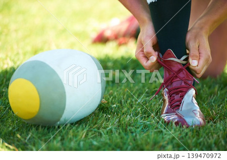 Rugby, ball and hands with shoes of person on field for training, practice and challenge. Health, start and games with closeup of sports athlete tying laces on outdoor pitch for stadium and fitness Rugby, ball and hands with shoes of person on field for training, practice and challenge. Health, start and games with closeup of sports athlete tying laces on outdoor pitch for stadium and fitness 139470972
