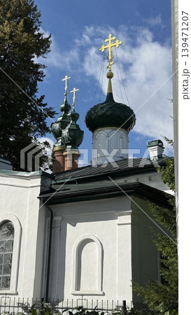 Orthodox church with green domes and golden crosses against blue sky and trees Orthodox church with green domes and golden crosses against blue sky and trees 139471207