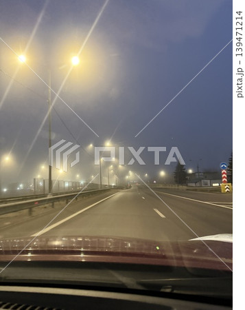 Streetlights illuminate foggy night road, creating a mysterious, serene background with a moody ambiance Streetlights illuminate foggy night road, creating a mysterious, serene background with a moody ambiance 139471214