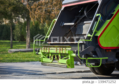 Modern green garbage truck parked on city street. Industrial vehicle for waste collection and recycling service. Professional municipal sanitization equipment for urban waste management. 139471252