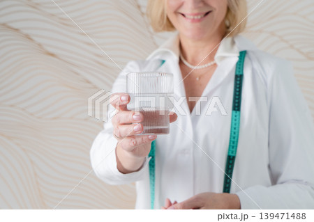 A professional woman elegantly holding a glass while also utilizing a measuring tape 139471488