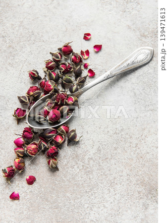 Dried rose buds and silver spoon on stone 139471613