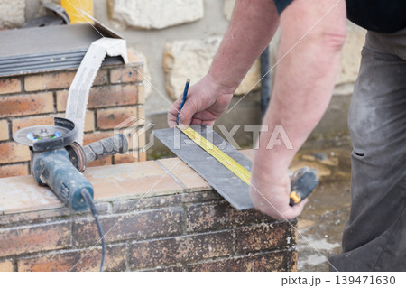 the tiler measures and puts marks to cut and lay a tile the tiler measures and puts marks to cut and lay a tile 139471630