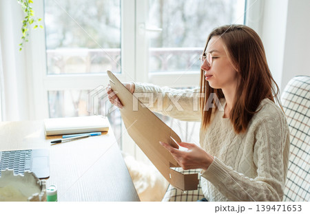 Woman opening a cardboard box Woman opening a cardboard box 139471653