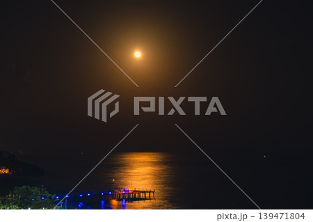 Moonlight Over Sea Waves Full Moon Glow ocean waves on sandy beach at night wooden pier. The moon illuminates water surface. Concept of beach vacation slowing down on seacoast Moonlight Over Sea Waves Full Moon Glow ocean waves on sandy beach at night wooden pier. The moon illuminates water surface. Concept of beach vacation slowing down on seacoast 139471804