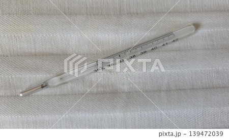 Glass mercury clinical thermometer on textured fabric background for medical illustration and health banner design 139472039