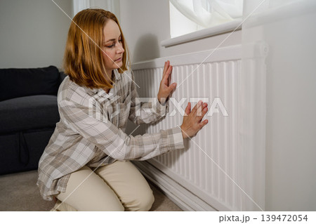 Woman warming up hands over heater. Increasing bills expenses. Cold season. Rising utility costs 139472054